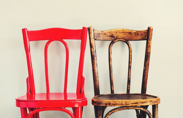 Dve drvene stolice od kojih je jedna ofarbana u crvenu boju.