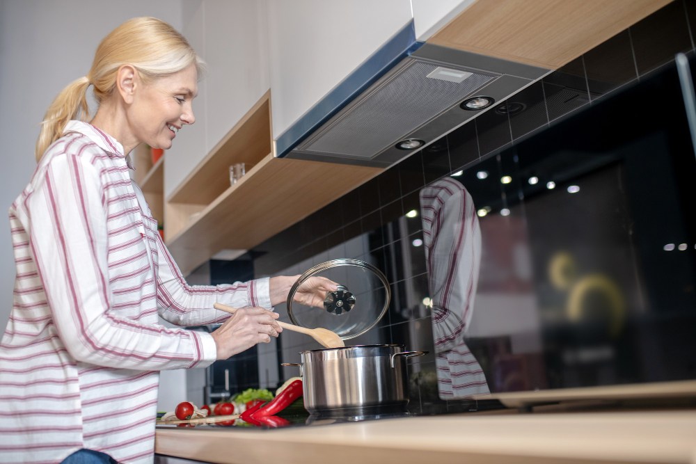 Žena vadi pleh iz rerne u kuhinji