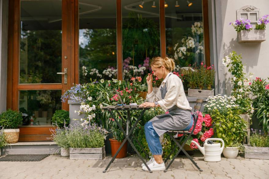 Žena sedi za stolom u dvorištu
