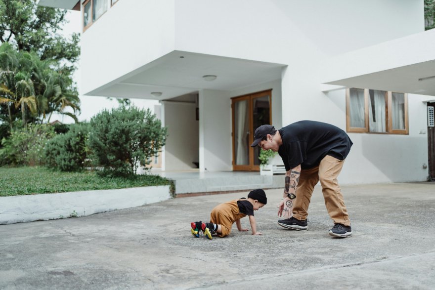 Otac se igra sa detetom na popločanom dvorištu