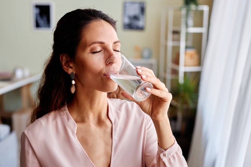 Žena pije čašu vode u stanu